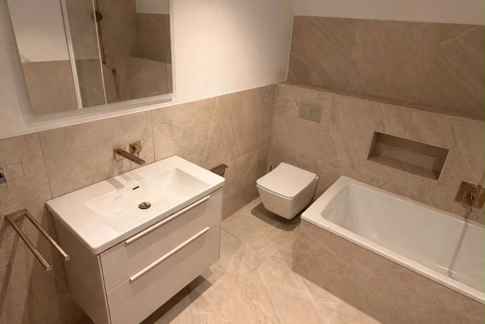 Großformatfliesen: Bad mit großen hellen Fliesen in Steinoptik, Waschtisch, Wand-WC und gefliester Wanne