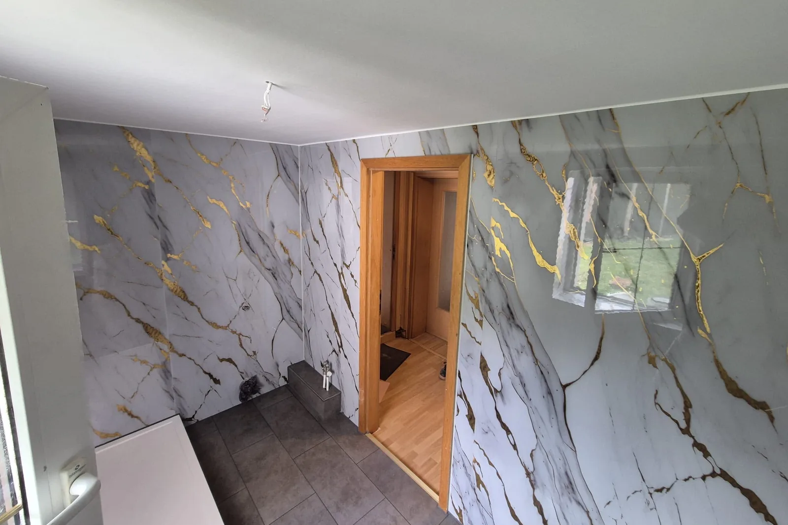 Große Wandplatten in Marmoroptik mit Goldadern anstelle von Fliesen