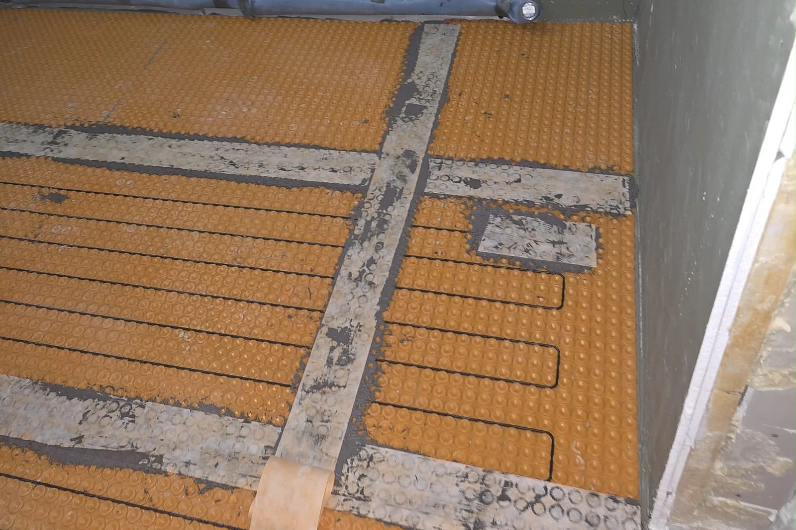 Fußbodenheizung: Elektrische Heizkabel in orangefarbener Entkopplungsmatte, vorbereitet zum Fliesen
