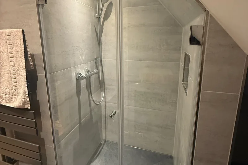 Duschabtrennung: Klarglastüren vor einer Dusche unter der Dachschräge
