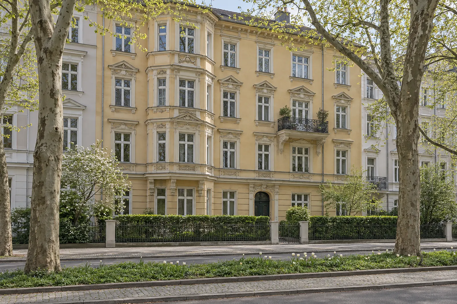 Altbaufassade der Gründerzeit mit Erker, davor eine Straße mit Grünstreifen
